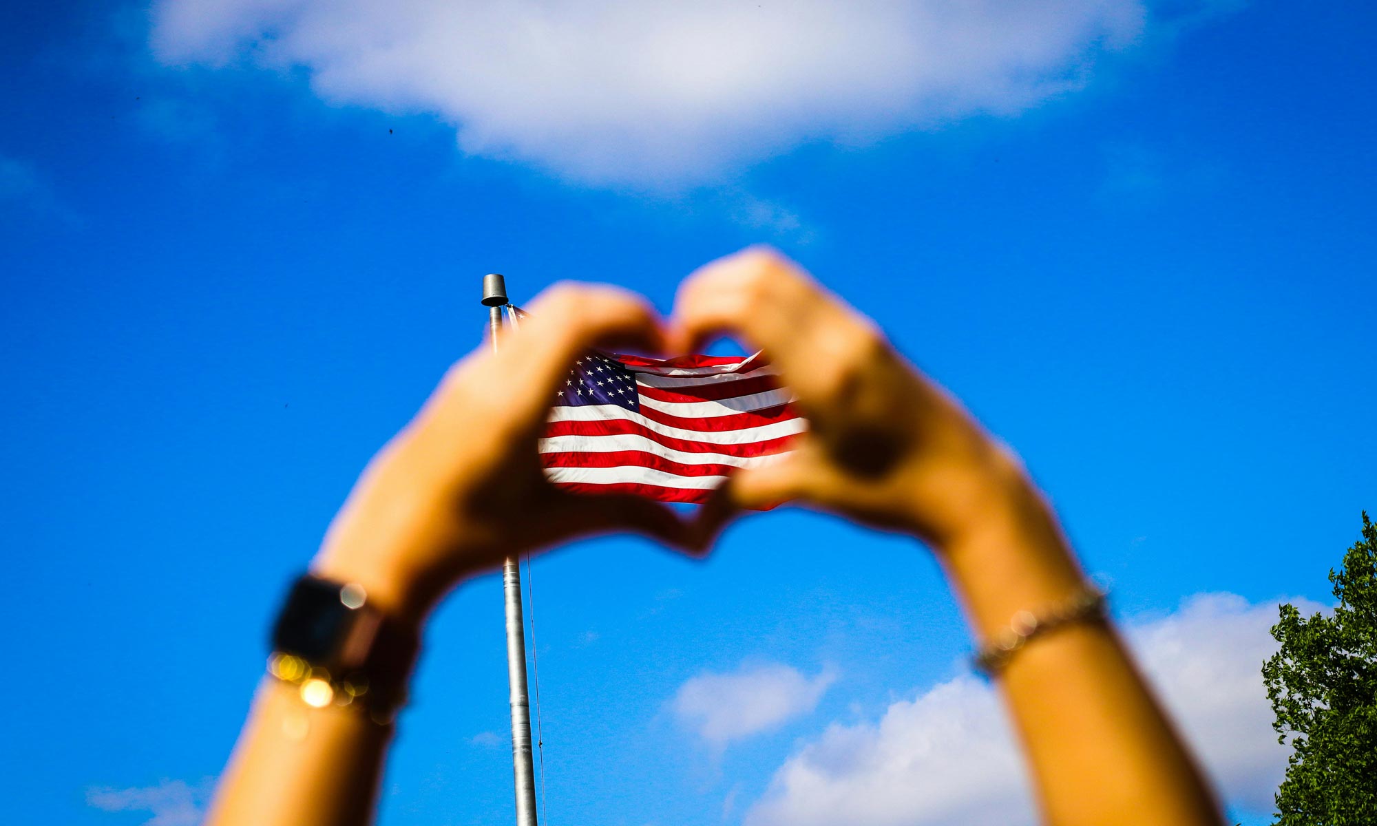 Hands making a heart shape with US flag in focus within the heart. This is a featured image for a blog post about politics and your DJ brand.